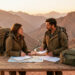 Deux voyageurs préparent des documents de voyage vierges et des bagages devant un paysage montagneux marocain illuminé par le coucher du soleil.